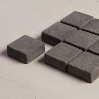 Side view of several charcoal coloured cobblestone pavers | Featured image for Cobblestone Paver.