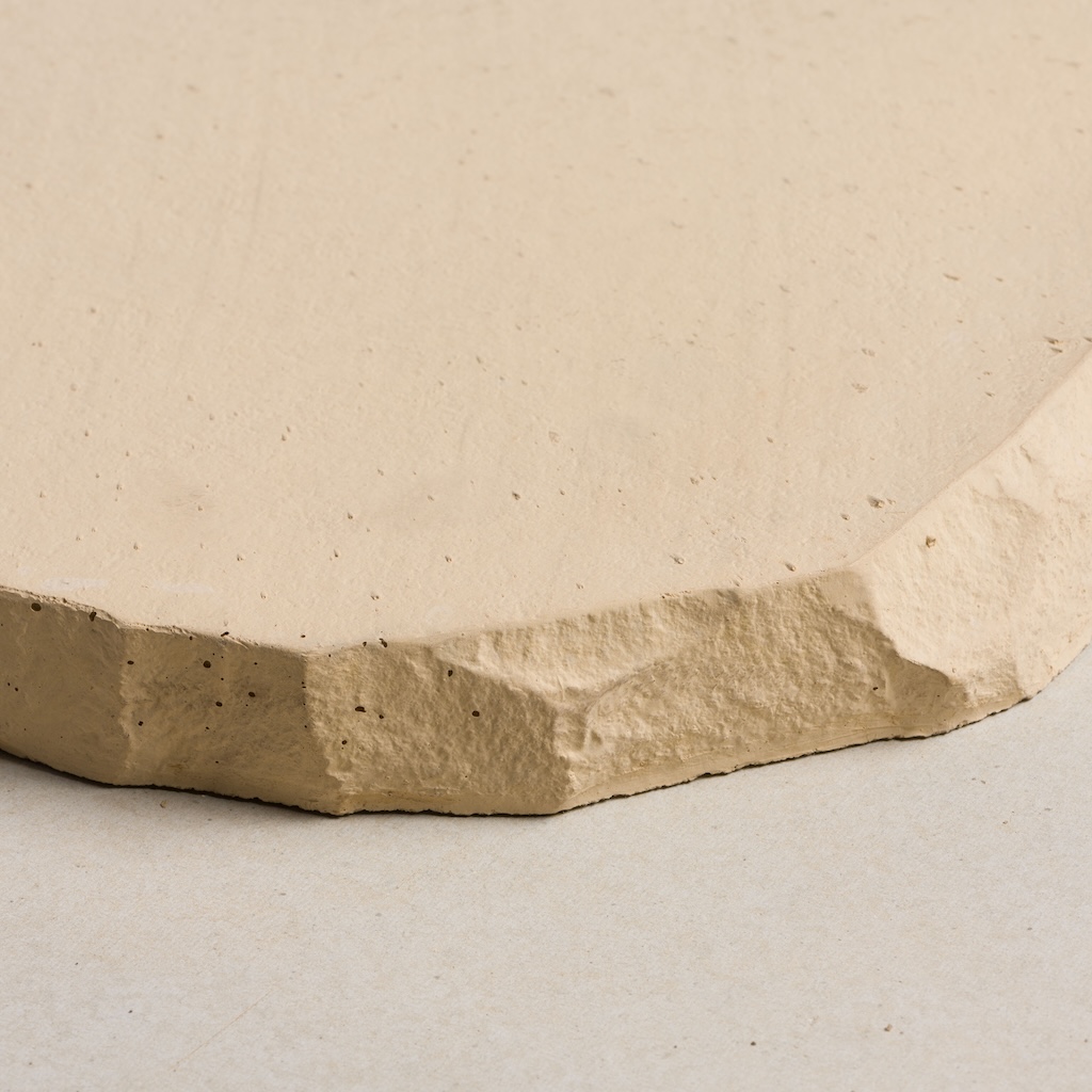 CentenaryLandscapePaversAug202_034 Light beige concrete paver with a textured, irregular edge and a smooth surface.