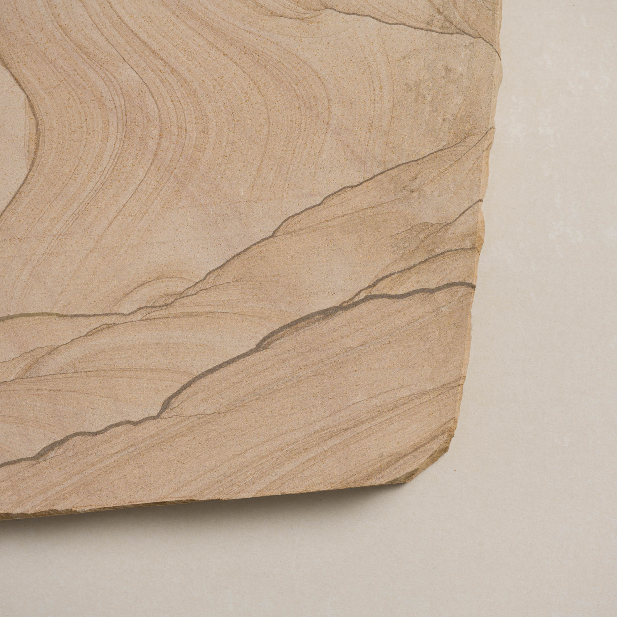 Natural sandstone stepper featuring smooth, wavy patterns in warm beige tones.