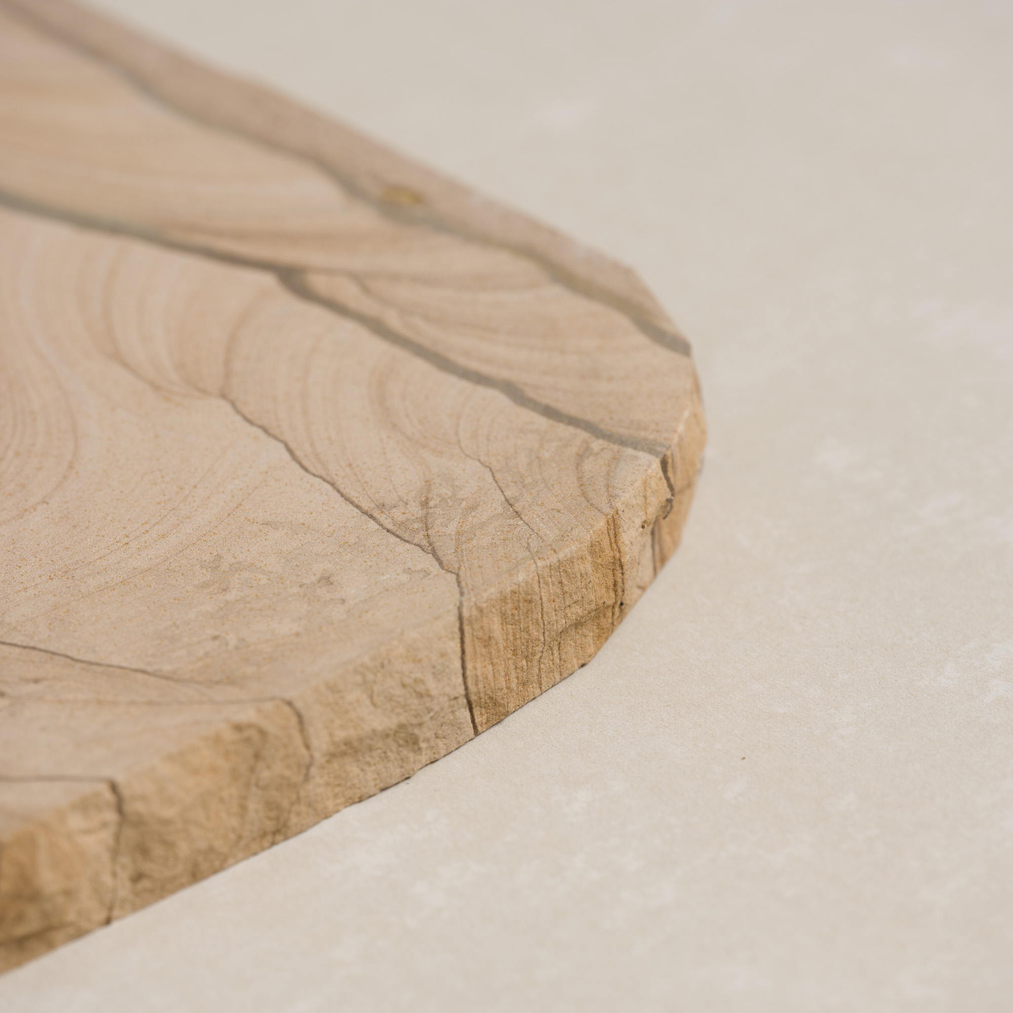 Natural sandstone stepper featuring smooth, wavy patterns in warm beige tones.