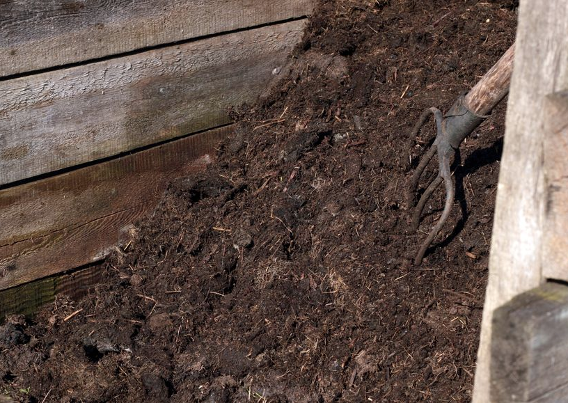 Pile of compost with a pitchfork in it | Featured image for the Composting at Home blog from Centenary Landscaping Supplies.